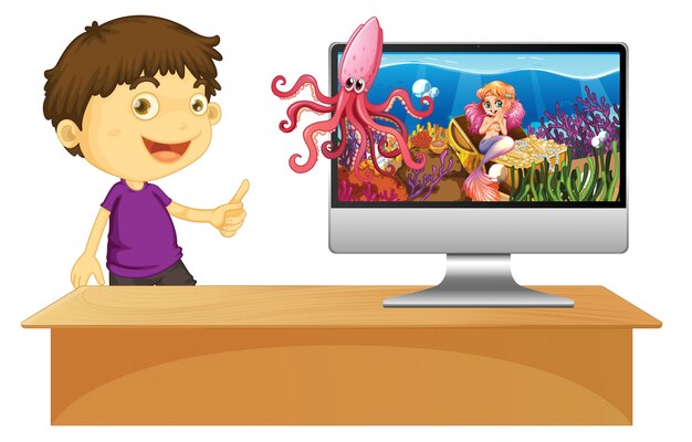 Niño feliz junto a la computadora con escena submarina en pantalla