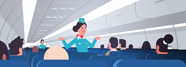 azafata explicando las instrucciones para pasajeros azafatas en uniforme mostrando salidas de emergencia concepto de demostración de seguridad interior del tablero del avión