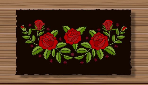 Bordado de flores con ramitas en una tela de solapa oscura y fondo de textura de madera. Adorno floral con puntadas rosas