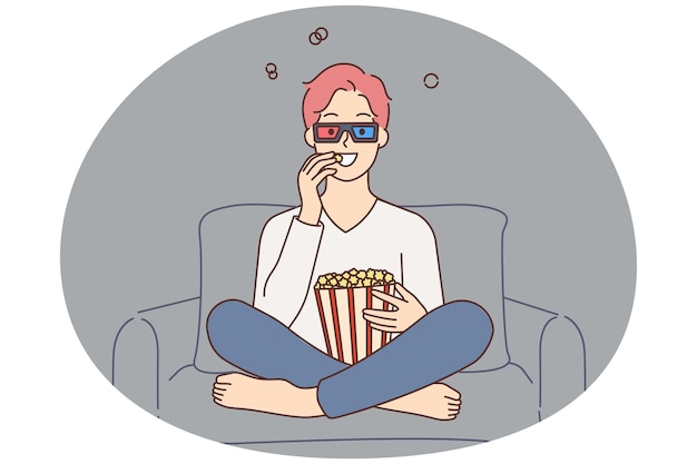 Chico sonriente viendo una película comiendo palomitas de maíz