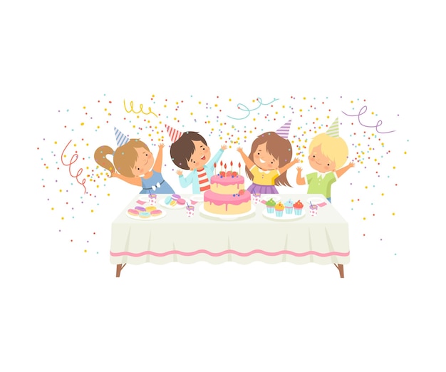 Chicos y chicas lindos divirtiéndose en la mesa festiva con pastel y confeti feliz fiesta de cumpleaños