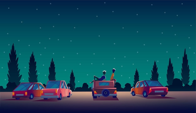 Conducir en el teatro con el stand de automóviles en el estacionamiento al aire libre por la noche