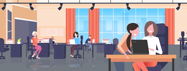 empresarios sentados en los escritorios del lugar de trabajo mujeres de negocios que utilizan el proceso de trabajo portátil concepto de trabajo en equipo moderno interior de la oficina horizontal de longitud completa