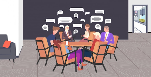 empresarios sentados en la mesa redonda charlando durante la reunión de redes sociales chat burbuja concepto de comunicación