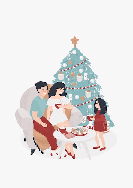 Familia con un niño bebe cacao junto al árbol de Navidad