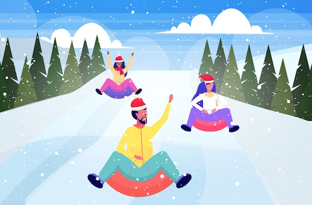 Gente con gorro de Papá Noel en trineo sobre nieve tubo de goma Navidad año nuevo vacaciones de invierno concepto de actividades amigos divirtiéndose paisaje de montañas nevadas