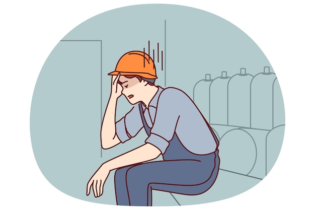 El hombre cansado que trabaja en la fábrica se sienta cerca del equipo de producción sosteniendo la cabeza debido al trabajo nervioso