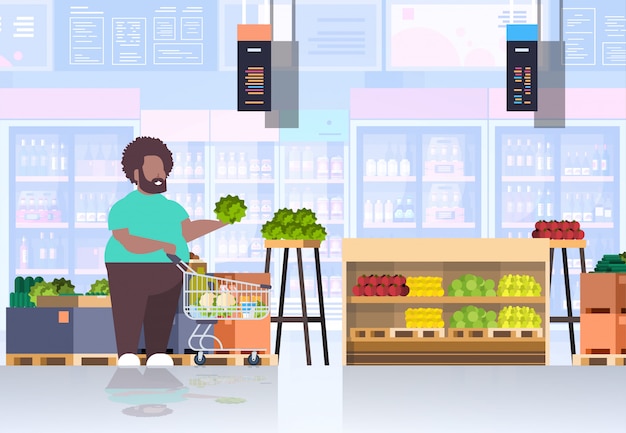 Hombre con carrito de compras carrito elegir verduras y frutas tipo supermercado concepto de cliente supermercado interior horizontal de longitud completa