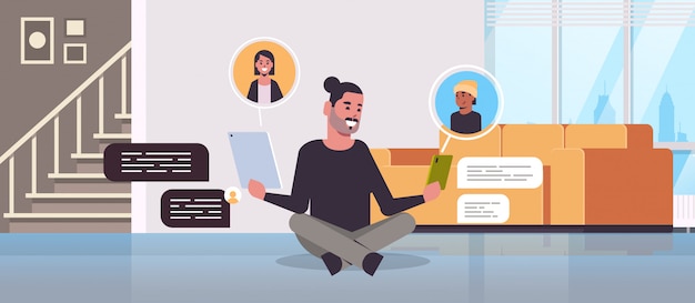 Hombre sentado en el piso usando aplicaciones de chat en dispositivos digitales concepto de comunicación de burbuja de chat de red social