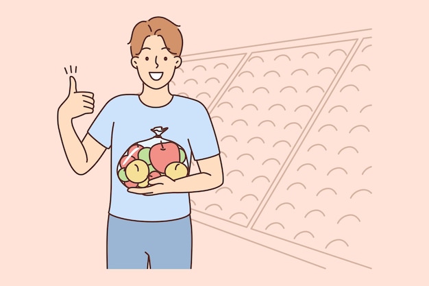 Hombre sonriente con bolsa de manzanas en el supermercado