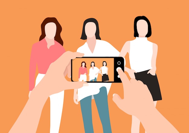 Las manos de un hombre tomando fotos de grupo de mujeres con un teléfono inteligente.
