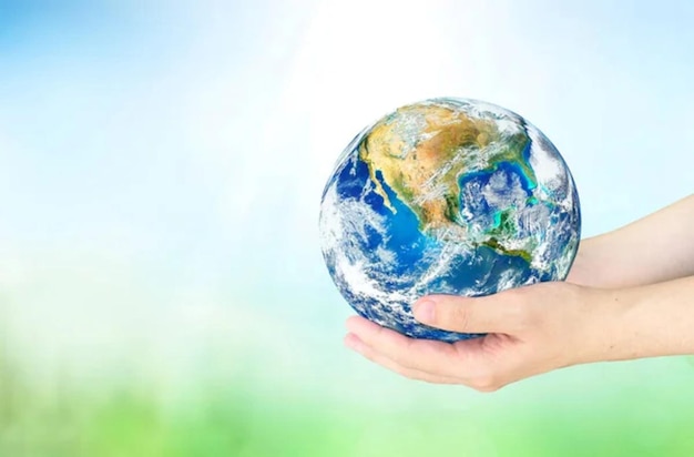 Las manos humanas del Día de la Tierra sosteniendo el globo en el fondo de la naturaleza