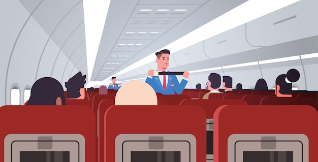 Mayordomo explicando a los pasajeros cómo usar el cinturón de seguridad en situaciones de emergencia asistentes de vuelo masculinos en concepto de demostración de seguridad uniforme tablero de avión moderno interior horizontal