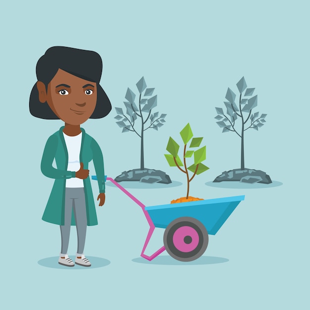 Mujer africana empujando la carretilla con planta.