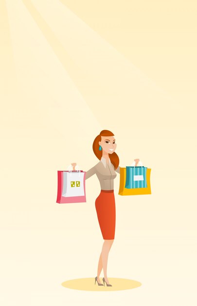 Mujer caucásica joven que sostiene bolsos de compras.