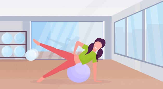 Mujer deportiva haciendo ejercicios con fitness ball entrenamiento de la niña en el gimnasio aeróbico pilates entrenamiento estilo de vida saludable concepto plano moderno club de salud studio interior horizontal