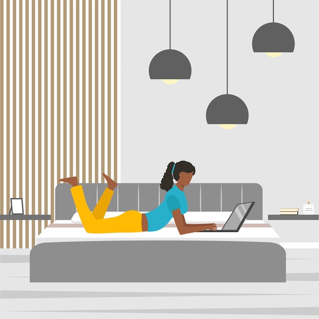 Mujer joven afroamericana acostada en la cama y usando una computadora portátil en casa