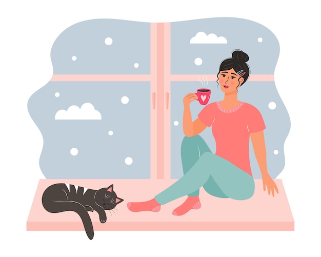 Mujer joven sentada en la ventana con una taza de bebida caliente y un lindo gato durmiendo cerca de su día de nieve