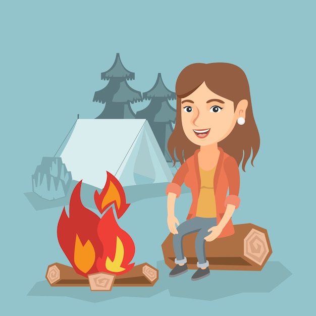 Mujer sentada en el registro cerca de la fogata en el camping.
