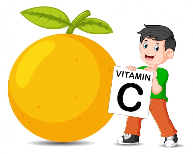 El niño al lado de la naranja sostiene el tablero de vitamina c.