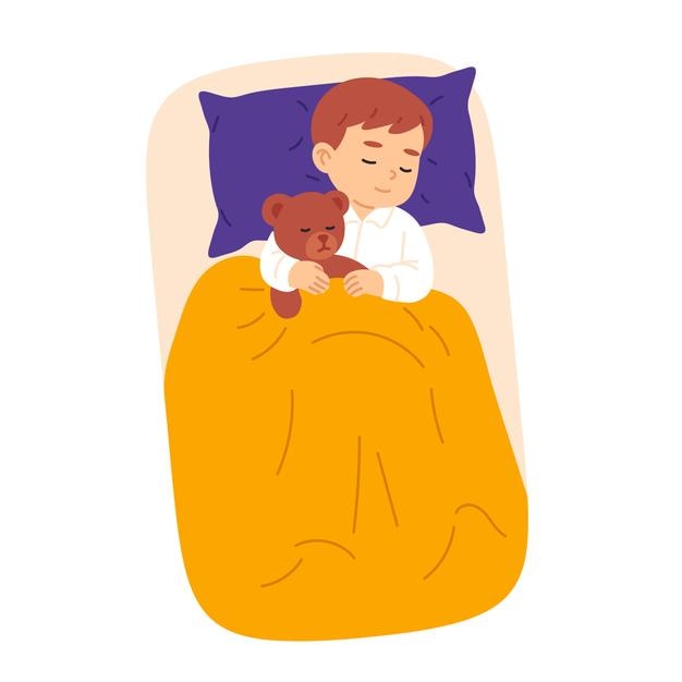 Niño durmiendo pacíficamente en la cama mientras abraza a un oso de peluche marrón bajo una manta amarilla