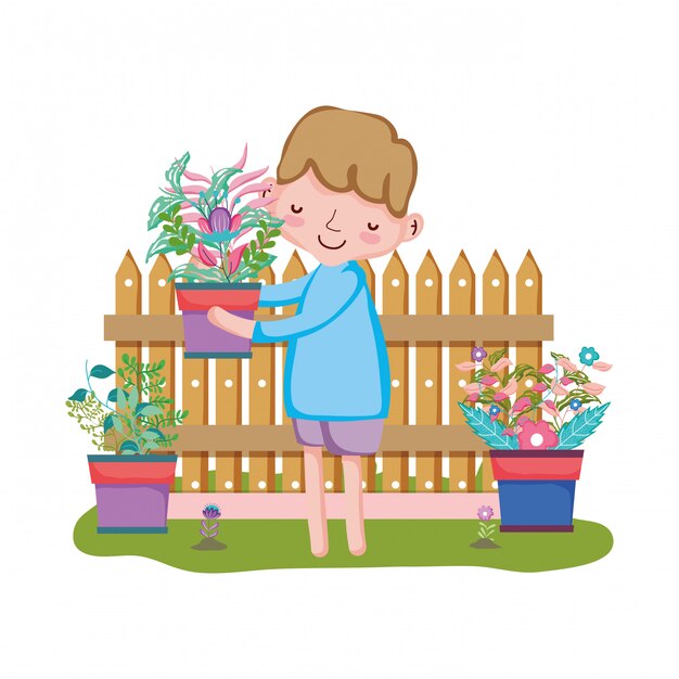 Niño levantando planta de interior con valla en el jardín