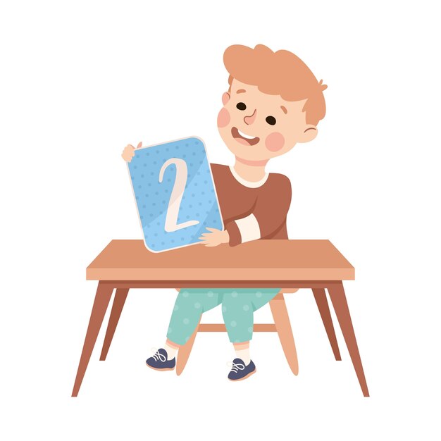 Niño pequeño con el número dos sentado en el escritorio mostrando una tarjeta con ilustración de vector numérico
