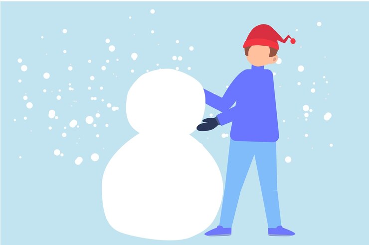 Un niño con un sombrero rojo crea un muñeco de nieve.