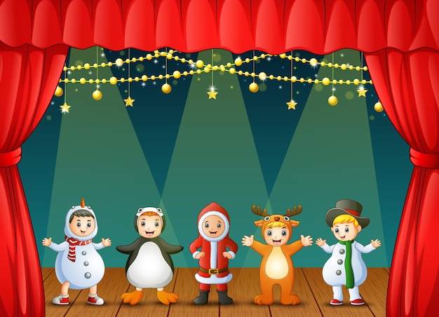 Niños felices con disfraces de Navidad actuando en el escenario