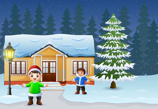 Niños felices jugando frente a la casa nevando