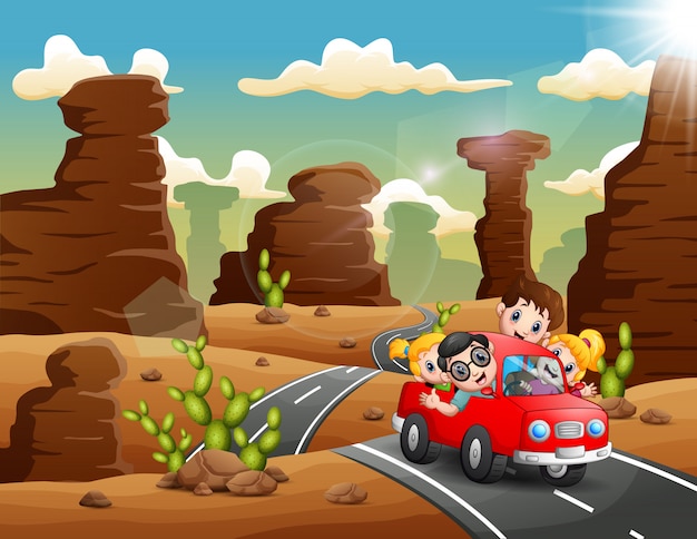 Niños felices viajando en coche rojo por el desierto.