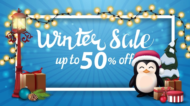 Oferta de invierno, hasta 50 de descuento, banner de descuento azul con marco blanco envuelto con guirnalda, farolillo viejo y pingüino con gorro de papá noel con regalos