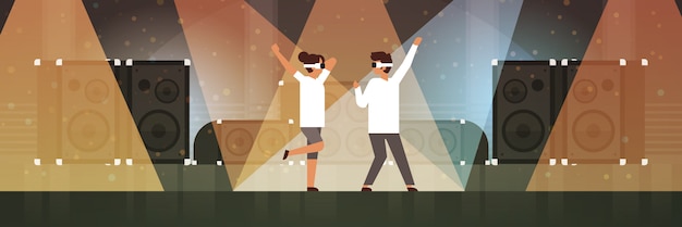 Pareja de bailarines con gafas de realidad virtual bailando en el escenario con efectos de luz discoteca estudio equipo musical altavoz multimedia