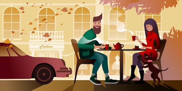 Pareja joven bebiendo té en la terraza de otoño del café de la ciudad. Escena callejera de la ciudad.