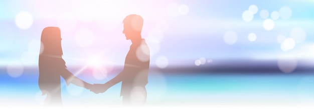 Pareja de silueta tomados de la mano en la hermosa playa borrosa Bokeh playa