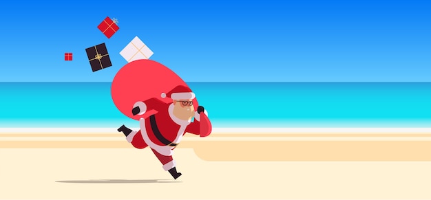 Santa claus corriendo con un gran saco lleno de regalos feliz año nuevo vacaciones de navidad celebración navideña concepto tropical beach seascape fondo plano de longitud completa ción