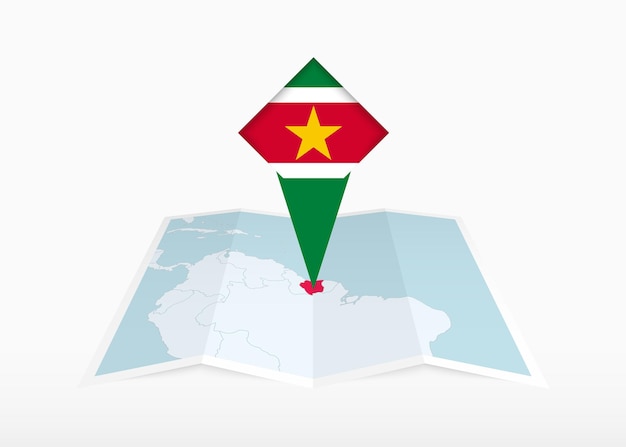 Surinam está representado en un mapa de papel doblado y un marcador de ubicación fijado con la bandera de Surinam