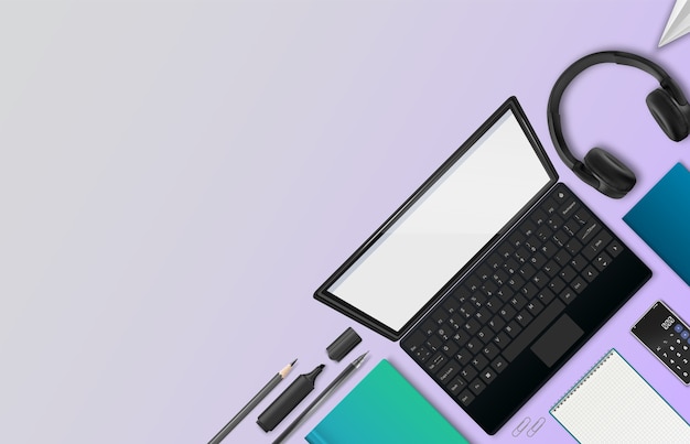 Workspace with laptop, headphones, notebooks, and stationery