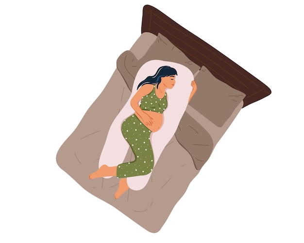 Draufsicht einer jungen schwangeren frau im schlafanzug, die auf einem mutterschaftskissen auf dem bett schläft.