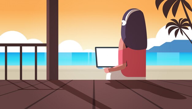 Frau mit laptop auf tropischen meer strand sommerferien online-kommunikation blogging-konzept rückansicht blogger sitzen auf holzterrasse seestück