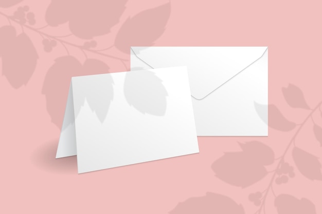 Weiße stehende Karte und Umschlagschablone mit Stechpalmenbeerenzweig mit Blattüberlagerungsschatten.