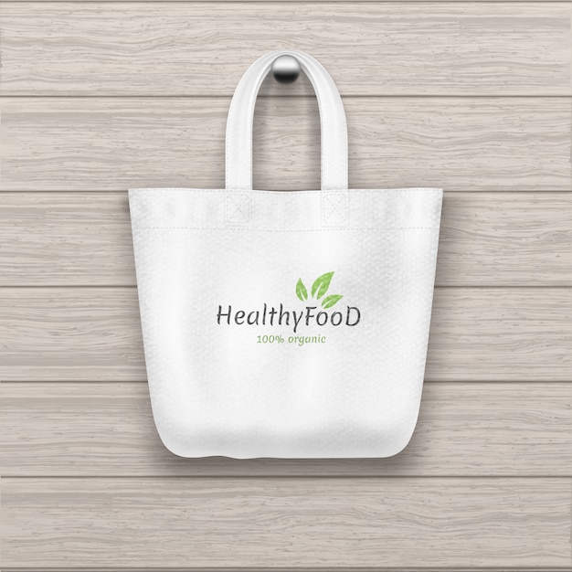 A matéria têxtil textured o bolsa branco com o saco do logotipo que pendura na prancha de madeira parede textured.