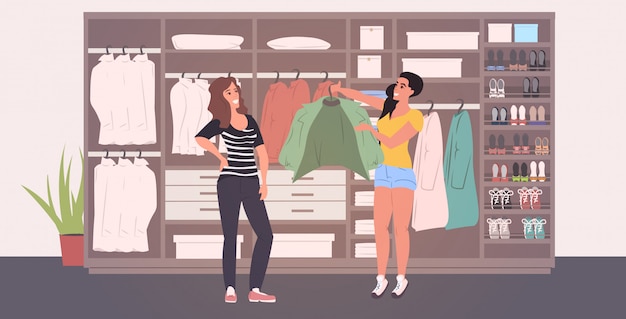 estilista de moda, ajudando a mulher a escolher roupa no guarda-roupa do vestiário com diferentes sapatos elegantes e roupas moderno interior do camarim comprimento total horizontal