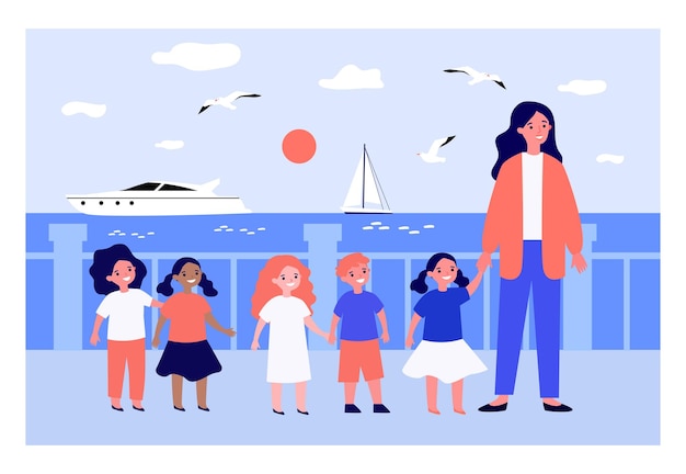 Grupo diversificado de crianças e professor caminhando no calçadão no mar