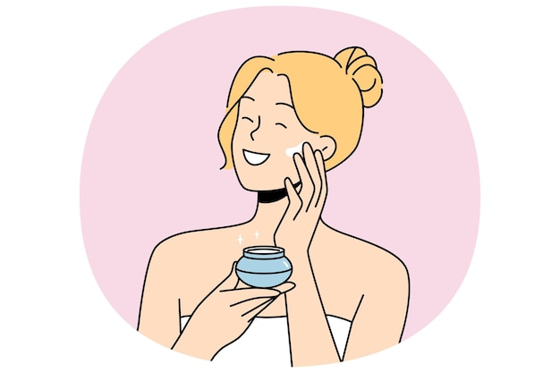 Mulher aplica creme anti-envelhecimento no rosto para ficar bonita de pé na toalha de banho depois do chuveiro
