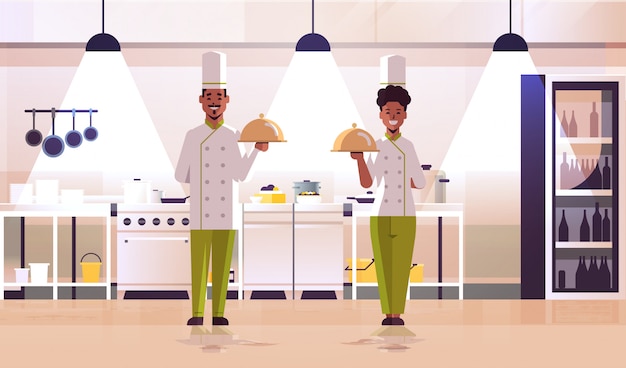 Vetor palavras-chave: profissional chefs pares segurando bandeja americano africano americano mulher bandeja homem estar uniforme uniforme alimento cozinha conceito interior