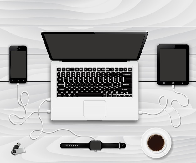 Smartphone, tablet e smartwatch carregados de um laptop