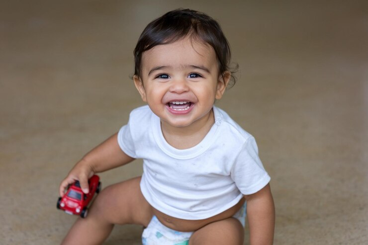 Vetor um bebê está sorrindo e vestindo uma camisa branca com um brinquedo vermelho
