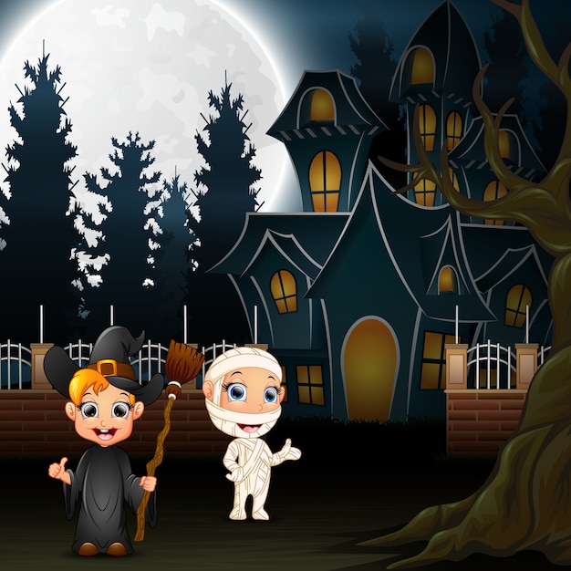 Bambini felici di halloween con casa spaventosa e luna piena