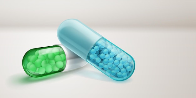 Capsule trasparenti di colore verde e blu con ombre morbide riempite di piccoli granuli di medicinale all' interno su una superficie bianca